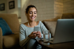 Young happy woman having fun while texting on mobile phone at home.